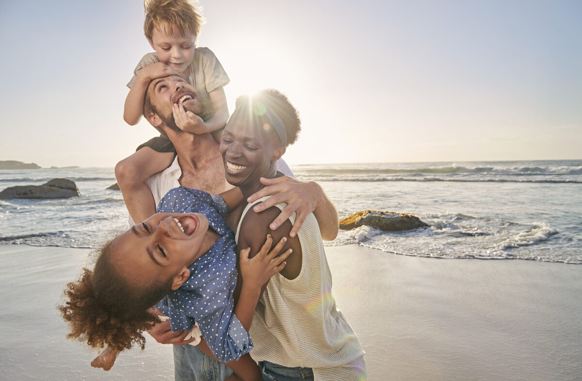 A joyful mixed-race family playing together on a sunny beach