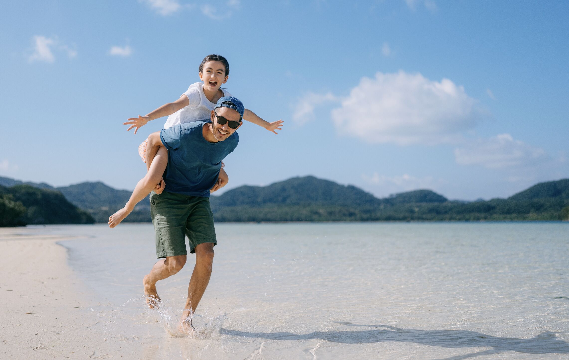 A father and daughter playing on a tropical beach